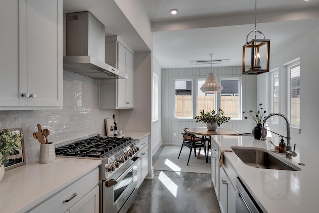 kitchen featuring sink, pendant lighting, white cabinetry, high end stainless steel range oven, and wall chimney range hood