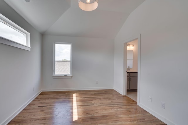 unfurnished room featuring lofted ceiling, sink, and light wood-type flooring