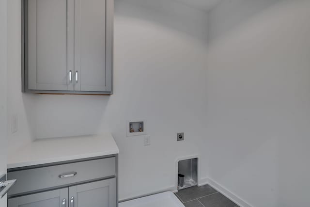 washroom featuring hookup for a washing machine, dark tile patterned floors, hookup for an electric dryer, and cabinets