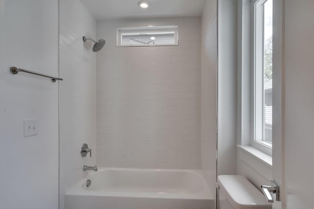 bathroom with toilet, tiled shower / bath combo, and a wealth of natural light