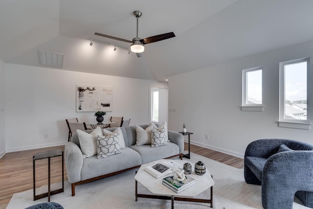 living room featuring ceiling fan, hardwood / wood-style flooring, vaulted ceiling, and a healthy amount of sunlight