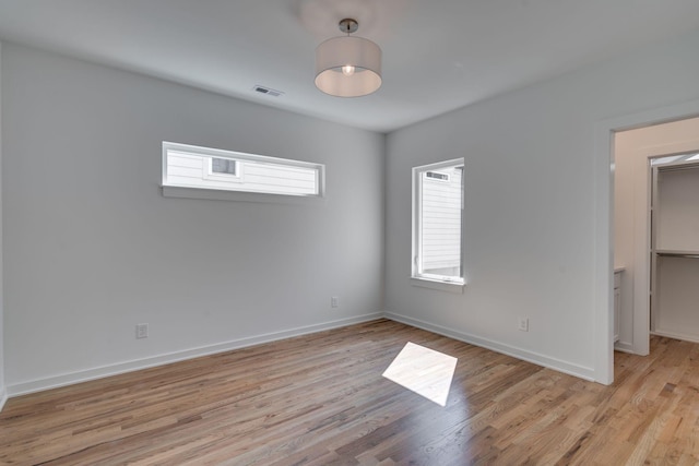 unfurnished bedroom featuring a walk in closet and light hardwood / wood-style flooring