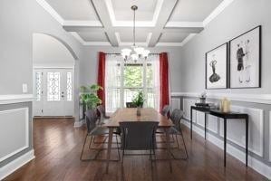 dining area featuring coffered ceiling, crown molding, beamed ceiling, dark hardwood / wood-style flooring, and a chandelier