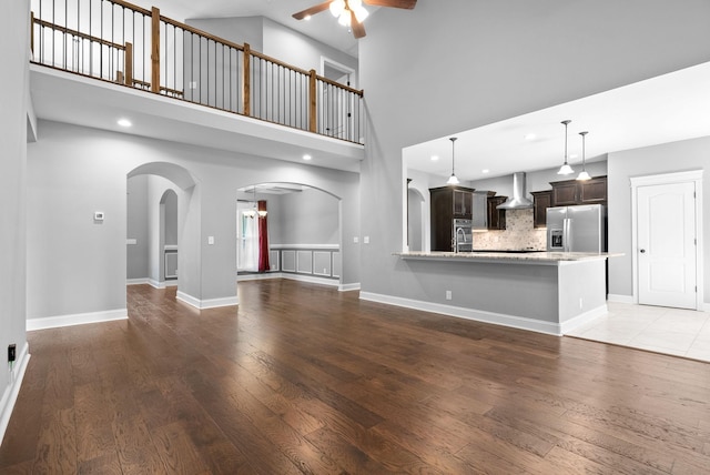 unfurnished living room with ceiling fan, hardwood / wood-style floors, a high ceiling, and sink