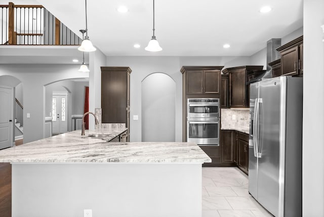 kitchen with dark brown cabinetry, sink, backsplash, decorative light fixtures, and appliances with stainless steel finishes