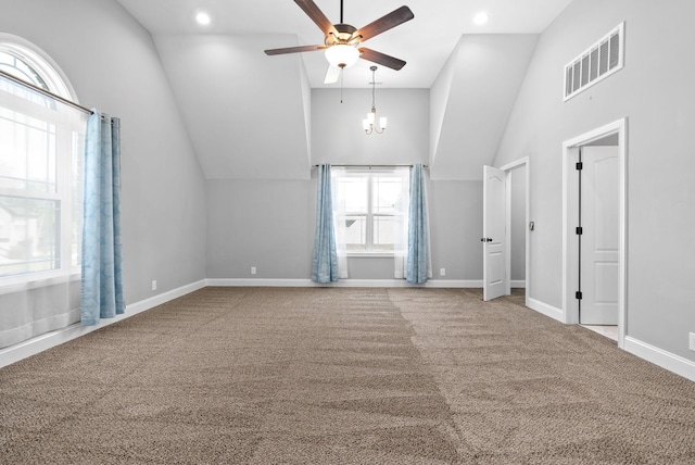 unfurnished living room featuring ceiling fan with notable chandelier, carpet floors, and high vaulted ceiling