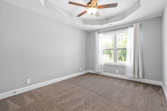 spare room with carpet, ceiling fan, and a raised ceiling