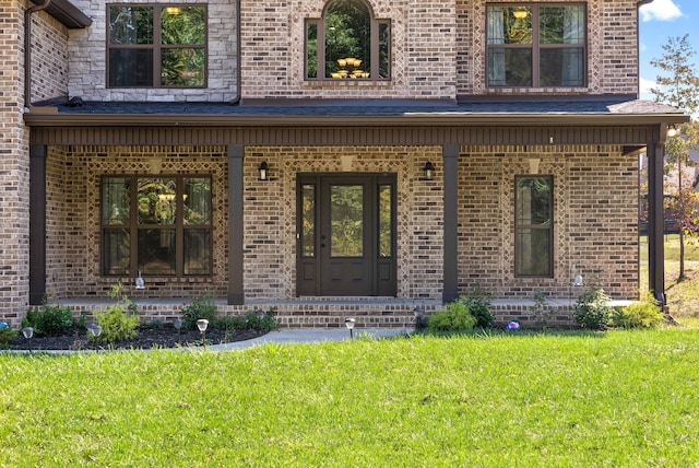 entrance to property with covered porch and a lawn