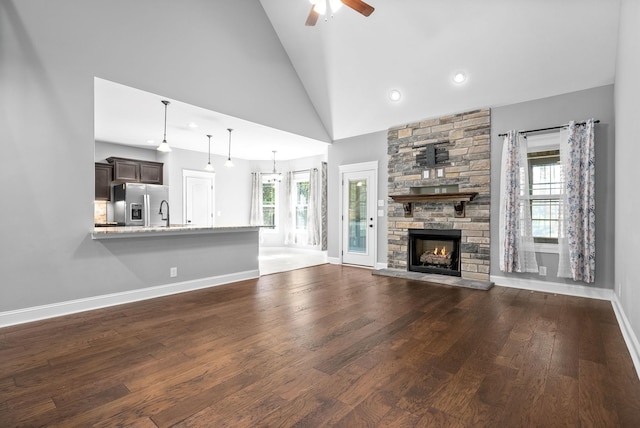 unfurnished living room featuring a fireplace, ceiling fan, plenty of natural light, and high vaulted ceiling