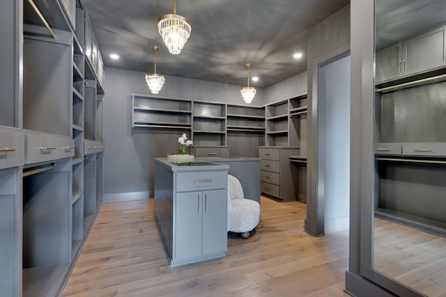 spacious closet featuring light hardwood / wood-style floors and a chandelier