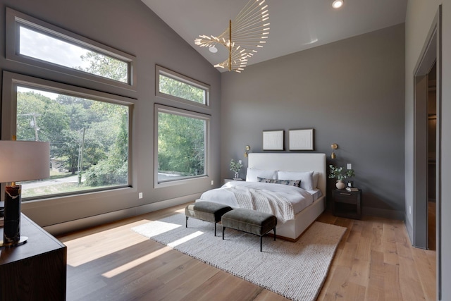 bedroom featuring vaulted ceiling, light wood-type flooring, and a chandelier