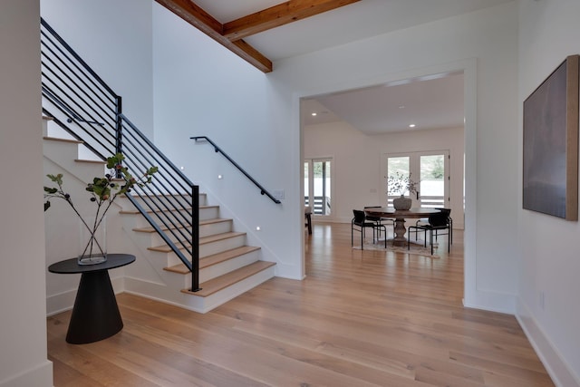 stairs with hardwood / wood-style floors and beamed ceiling