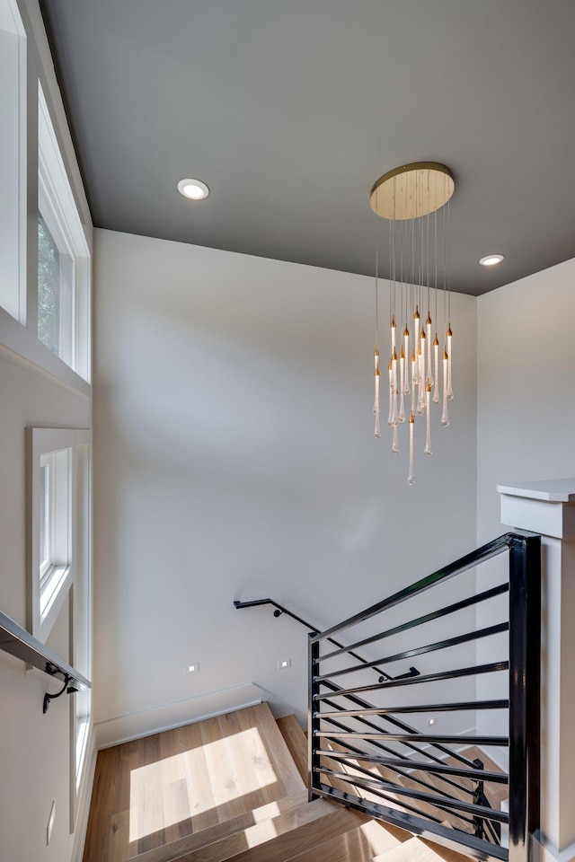 stairs featuring wood-type flooring and a notable chandelier