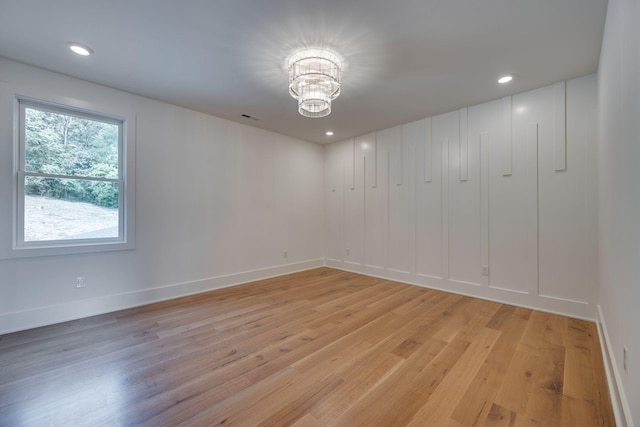 spare room with light hardwood / wood-style flooring and a notable chandelier