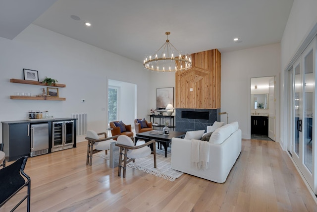 living room with light hardwood / wood-style floors, wine cooler, and a chandelier