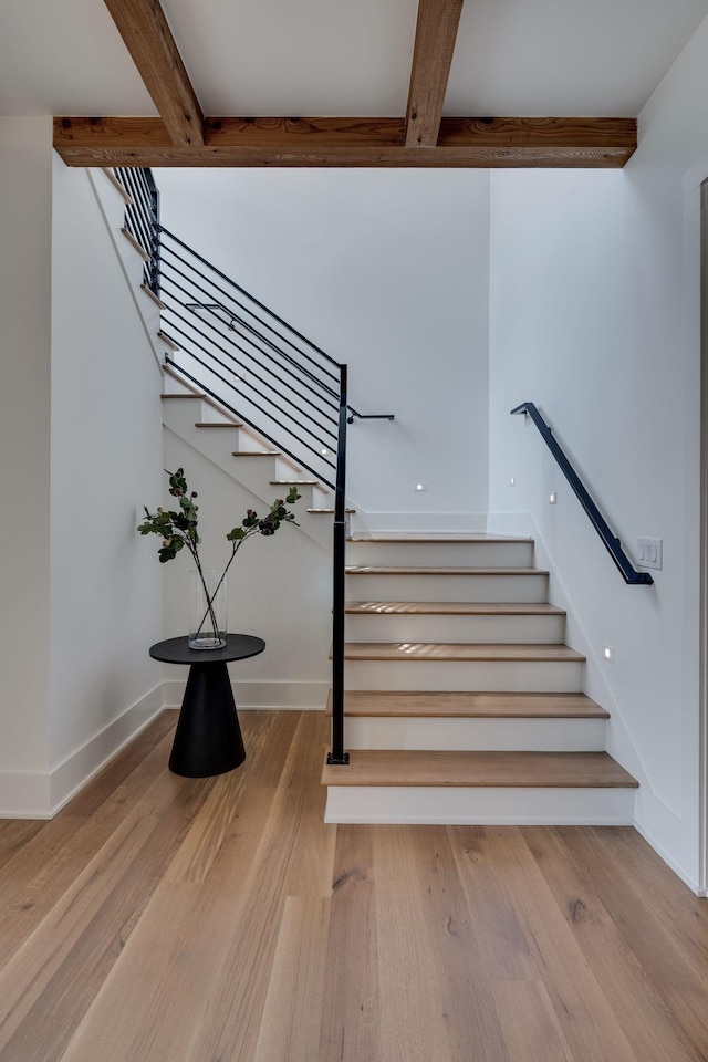 stairway featuring beam ceiling and hardwood / wood-style flooring