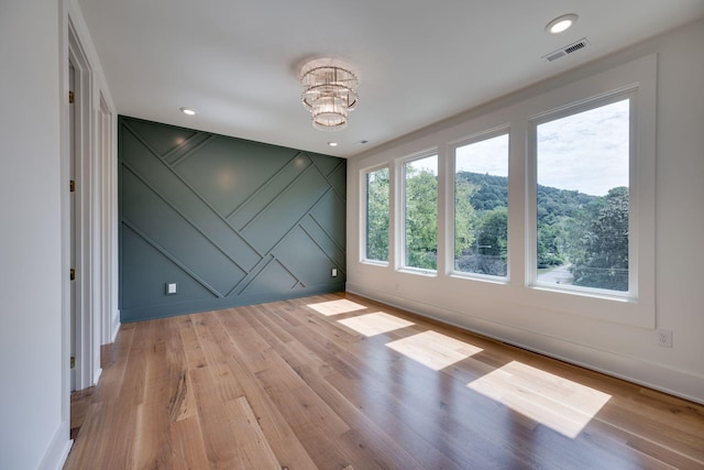 unfurnished room featuring light wood-type flooring and a notable chandelier