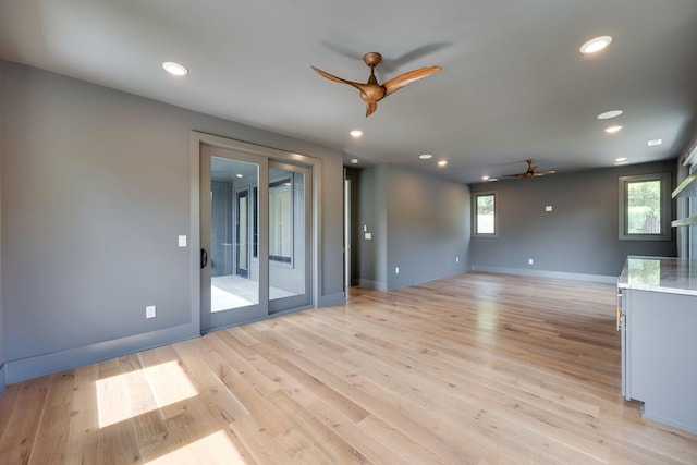 unfurnished living room with ceiling fan and light wood-type flooring