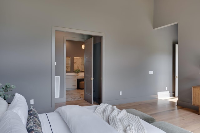 bedroom with connected bathroom and light wood-type flooring