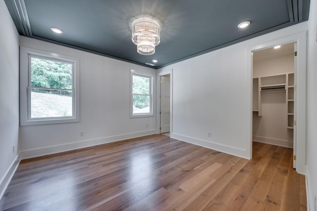 unfurnished bedroom with a walk in closet, a closet, multiple windows, and a notable chandelier