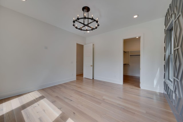 empty room with a chandelier and light hardwood / wood-style floors