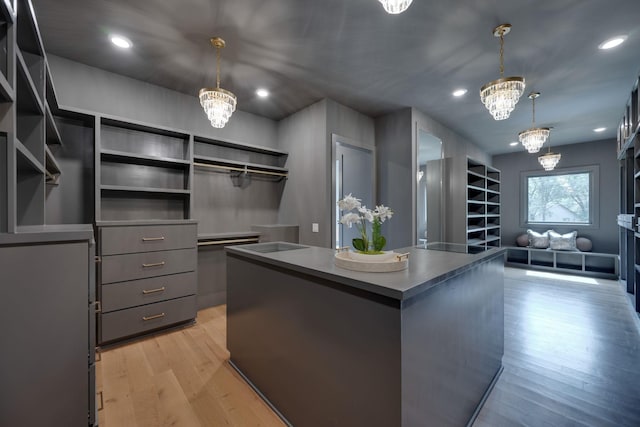 walk in closet featuring light wood-type flooring and a chandelier