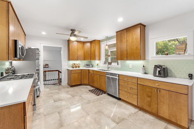 kitchen with backsplash, stainless steel appliances, ceiling fan, sink, and decorative light fixtures