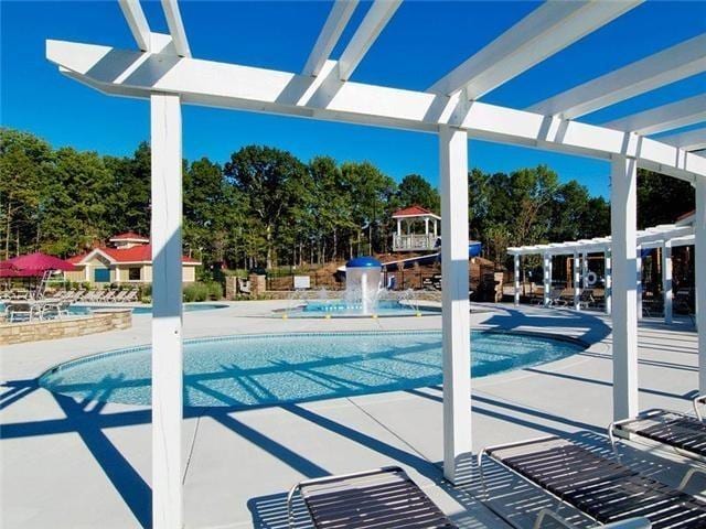 view of pool featuring a pergola, pool water feature, and a patio