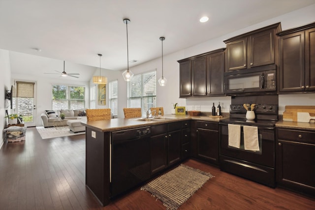 kitchen with sink, dark wood-type flooring, kitchen peninsula, pendant lighting, and black appliances