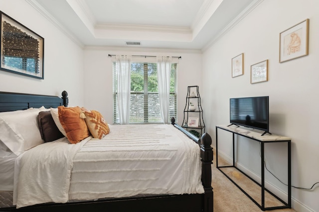 carpeted bedroom with ornamental molding and a tray ceiling