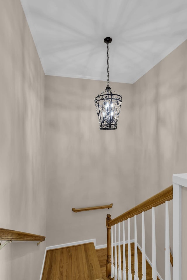 stairs featuring hardwood / wood-style flooring and an inviting chandelier