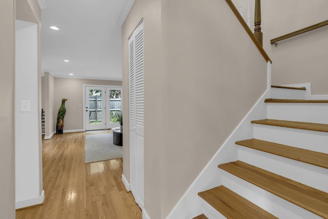 stairs with hardwood / wood-style flooring and crown molding