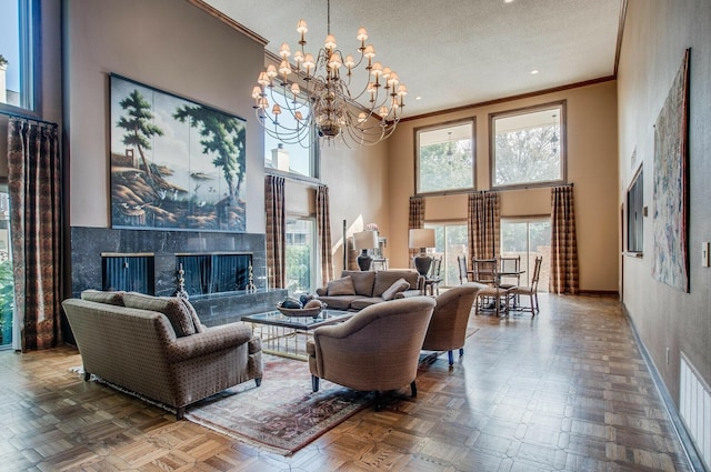 living room featuring a tile fireplace, parquet floors, a high ceiling, a chandelier, and a textured ceiling