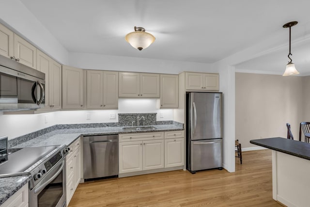 kitchen with light wood-type flooring, stainless steel appliances, hanging light fixtures, and sink