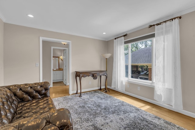 living area featuring crown molding and light hardwood / wood-style floors