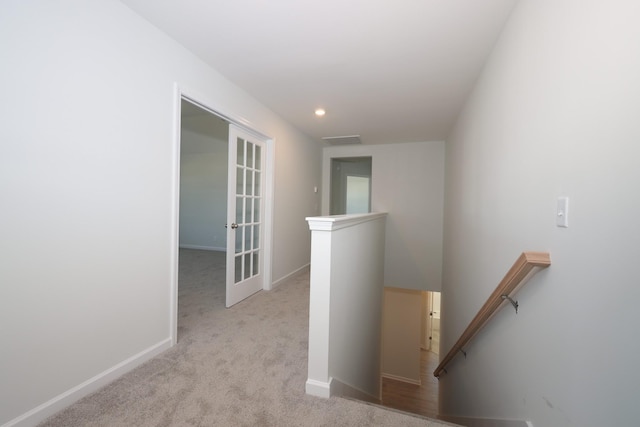 corridor with light carpet and french doors