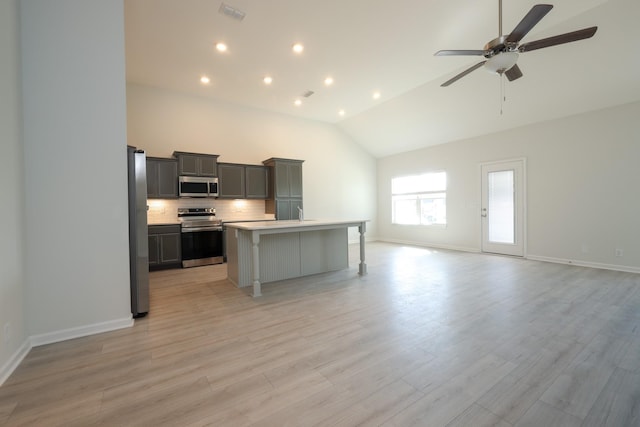 kitchen with a kitchen island, appliances with stainless steel finishes, a breakfast bar, tasteful backsplash, and gray cabinetry