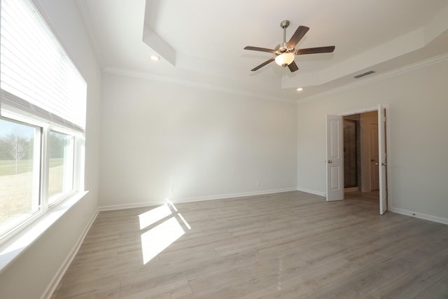 empty room featuring ornamental molding, a tray ceiling, and light hardwood / wood-style flooring