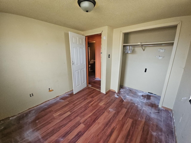 unfurnished bedroom with a textured ceiling, a closet, and dark wood-type flooring