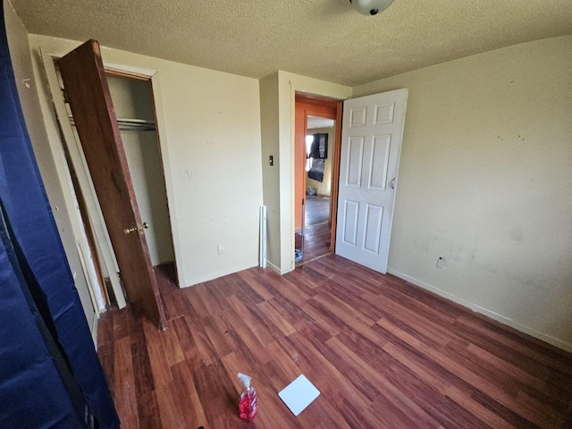 unfurnished bedroom featuring a textured ceiling, dark hardwood / wood-style floors, and a closet