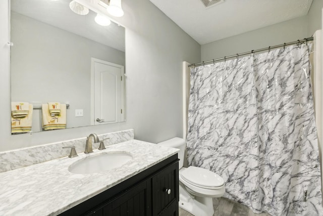 bathroom with vanity, a shower with shower curtain, and toilet