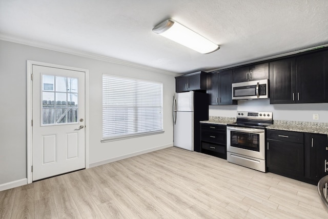 kitchen with stainless steel appliances, light stone counters, light hardwood / wood-style flooring, a textured ceiling, and ornamental molding