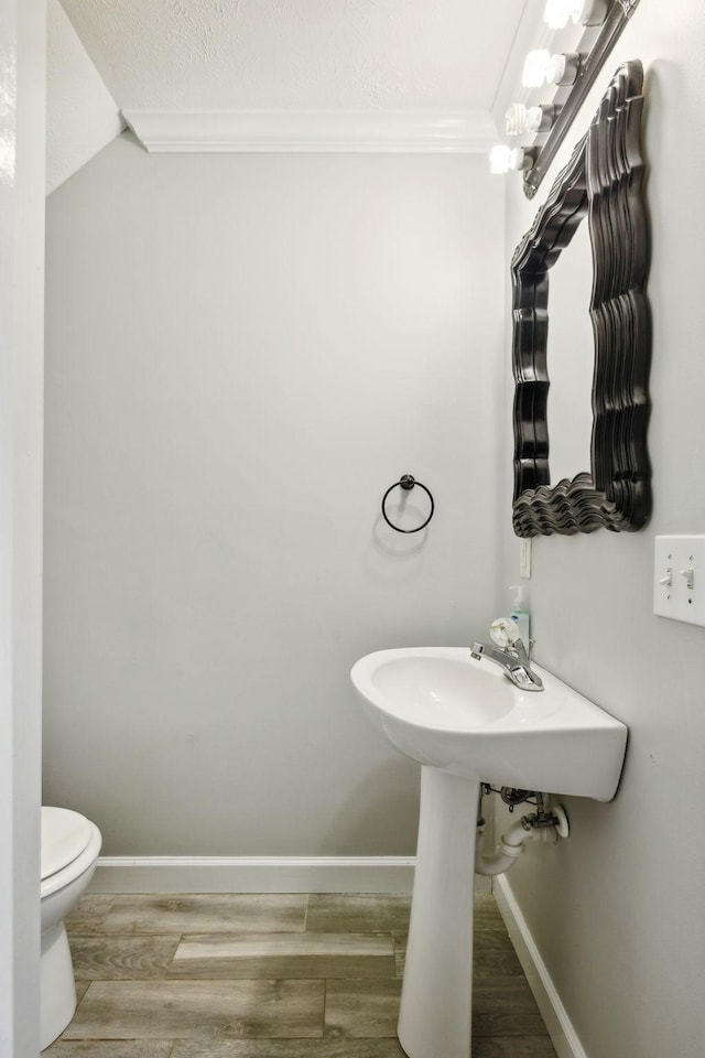 bathroom with hardwood / wood-style flooring, crown molding, a textured ceiling, and toilet