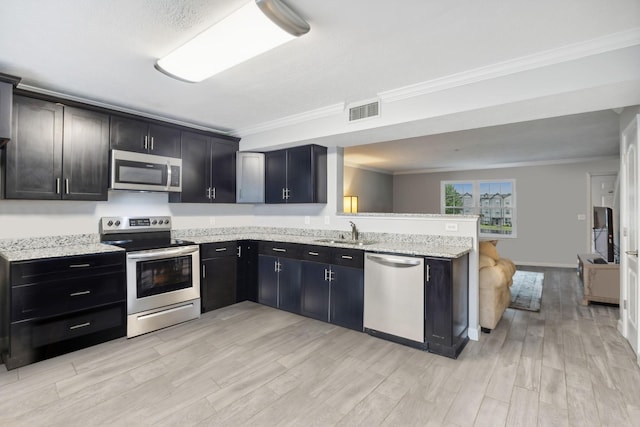 kitchen with sink, ornamental molding, light stone counters, kitchen peninsula, and stainless steel appliances