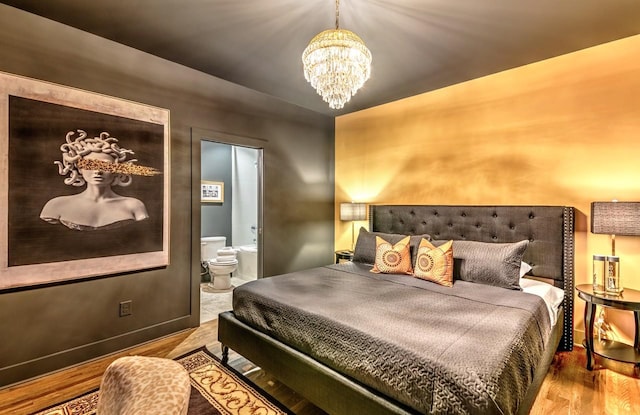 bedroom featuring an inviting chandelier, ensuite bath, and hardwood / wood-style flooring