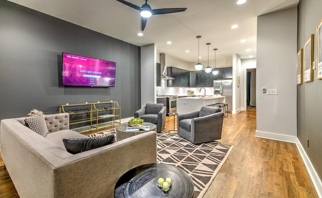 living room featuring ceiling fan, sink, and hardwood / wood-style flooring