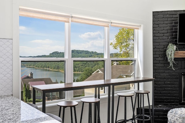 dining area with a water view, a fireplace, and a wealth of natural light