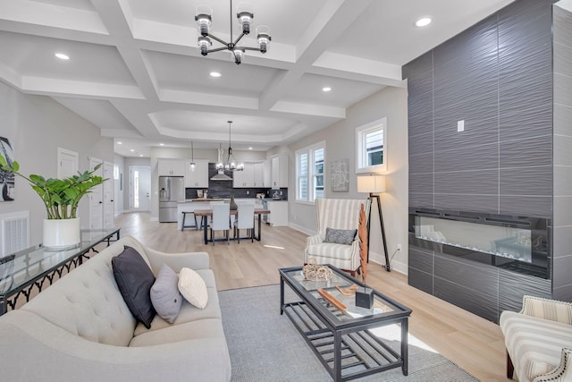 living room featuring beamed ceiling, light hardwood / wood-style floors, a notable chandelier, and coffered ceiling