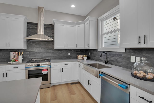 kitchen featuring white cabinets, sink, stainless steel appliances, and wall chimney range hood