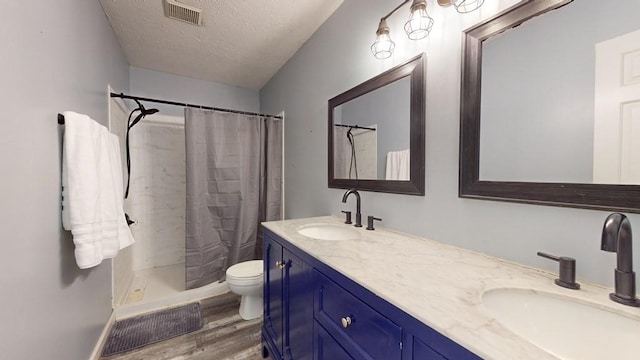 bathroom with a shower with curtain, a textured ceiling, toilet, vanity, and hardwood / wood-style flooring